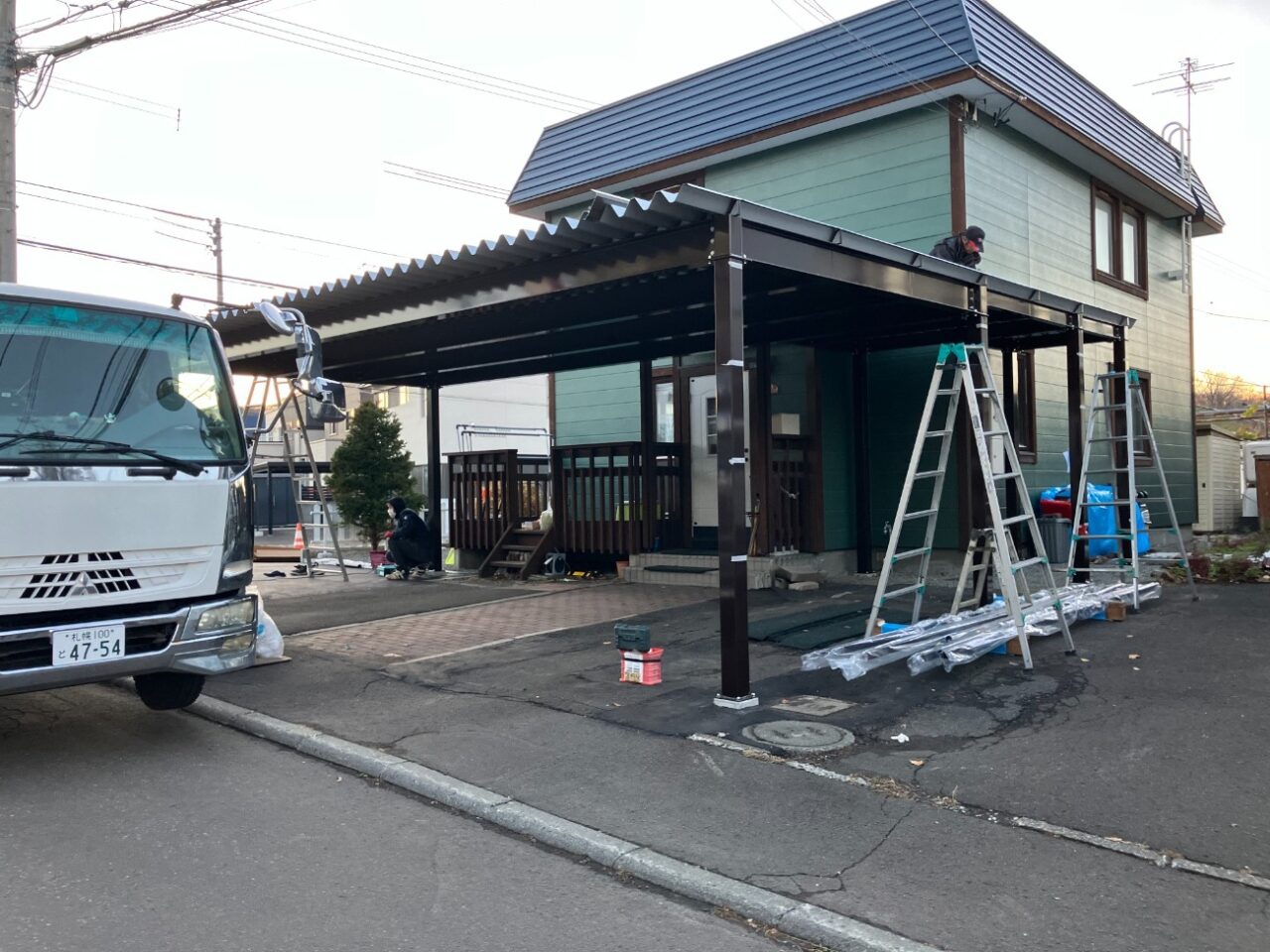 既存の庭部分を整理し、駐車スペースとして活用できるよう地面を整えていきます。あわせて、これまで使用していた1台用カーポートを撤去し、新しいカーポートを設置するためのスペースを確保しました。 その後、特別注文の鉄骨3台用カーポート「AP760L型」を設置していきます。柱や梁を組み上げながらカーポート全体を施工し、3台分の車を駐車できる屋根付きスペースを整えました。 カーポートの設置にあわせて、敷地境界には既存と同様にアルミフェンスを設置しています。庭だった部分まで駐車スペースとして活用できるよう、外構全体を整えていきました。